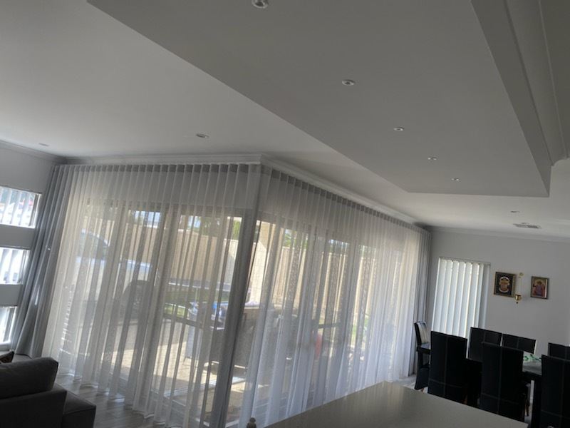 Sheer curtains running across a wide corner window in a living area